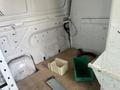 A 2008 Ford Econoline van interior showing bare walls and a wooden floor with two bins and some tools on the ground