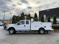 A white 2013 Ford F-350 Super Duty truck with a utility bed and equipment mounted in the back