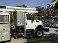 A 2013 International 7400 truck with a silver exterior and specialized equipment including hoses and storage compartments attached to its side