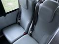 Two gray upholstered seats with seatbelts inside a vehicle