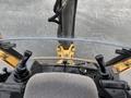 Interior view of a 2011 John Deere 310SJ 4x4 Wheel Loader displaying the control levers and seat with a clear view of the extended hoe and 4 in 1 bucket
