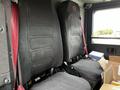 The interior of a 2009 Spartan Gladiator featuring two high-backed black seats with red seatbelts and a box on the floor between them