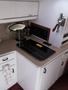 A 1991 Larson Mirado boat interior featuring a compact kitchenette with a sink a microwave and a glass cooktop on a beige countertop