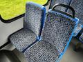 Two blue and patterned fabric seats inside a vehicle with a gray floor and large windows