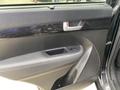 Interior door panel of a 2015 Kia Sorento featuring a speaker grill window control buttons and a fabric texture