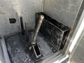 A metal compartment with a lever and several vertical rods visible inside a vehicle setup