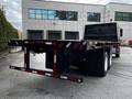 A red and black 2011 International 4400 flatbed truck with rear lights and a sharp angled back design parked in a lot