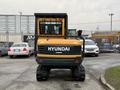 A 2022 Hyundai R55-9A compact excavator with a yellow and green exterior facing forward and tracks for mobility