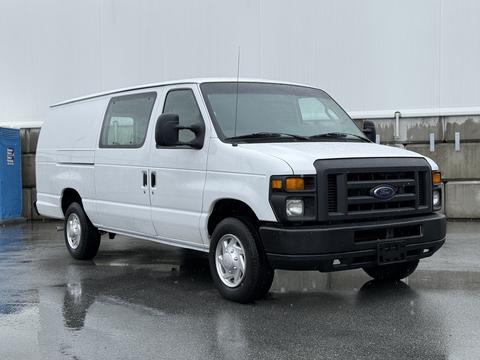 A white 2013 Ford Econoline van with a simple design and front grille is parked with its side doors slightly ajar