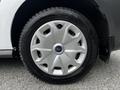A close-up of a silver wheel with five circular openings and a blue Ford logo in the center, mounted on a tire with tread patterns