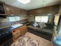 Interior of a 2014 Launch 24RLS travel trailer featuring a compact kitchen with a sink and stove a sofa with throw pillows and various storage cabinets