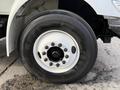 A large black tire with a white rim featuring multiple bolts, mounted on a 2011 International 4300 truck