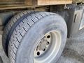 A close-up view of a large truck tire featuring a prominent tread pattern mounted on a metallic rim