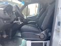 Side view of the interior of a 2025 Mercedes-Benz Sprinter showing driver and passenger seats with fabric upholstery and a dashboard with controls