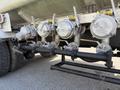 A series of four metal valves mounted on a black pipe connected to a vehicle displaying industrial components and fittings