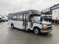 A 2017 Chevrolet Express bus with a gray exterior and large windows positioned at an angle on a wet surface