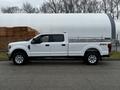 A white 2020 Ford F-350 SD truck is parked on the street with a long bed and chrome wheels