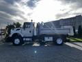 A white 2011 International 7500 truck with a dump bed is parked on a concrete surface facing right