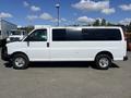 A white 2012 Chevrolet Express van is parked, featuring a long body, sliding door on the side, and chrome wheel rims