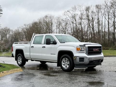 A white 2015 GMC Sierra 1500 pickup truck parked on a wet surface with a double cab and chrome accents