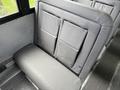 A gray upholstered bench seat inside a vehicle with two high backs and a wide cushion, designed for passenger seating.