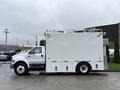 A white 2011 Ford F-650 truck with a boxy cargo area and no visible markings parked on a wet surface