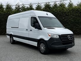 2019 Mercedes-Benz Sprinter van with a white exterior and black accents parked at an angle showing the front and side profile
