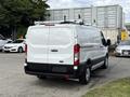 White 2023 Ford Transit van with a roof rack viewed from the rear showcasing its cargo space and clean design