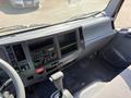 Interior view of a 2013 Isuzu NPR showing the dashboard controls radio and gear shift with a gray color scheme