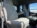 Interior of a 2004 Freightliner M2 showing two fabric seats with a gray pattern and a partial view of the driver's seat with controls and armrests visible
