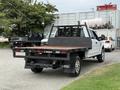 A white 2019 Ford F-350 SD with a flatbed and black side rails is parked, showcasing its rear and bed design