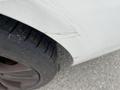 A close-up of the tire and lower body of a 2011 BMW 3-Series showing a scratch on the body and detailed tread pattern on the tire