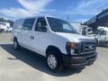 A 2009 Ford Econoline van with a white exterior and black front grille is parked, displaying a simple and functional design