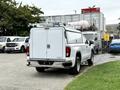 A white 2022 GMC Sierra 1500 pickup truck with a utility bed cap and ladder racks on top parked on a paved surface