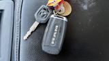 A black RAM key fob with the RAM logo and a silver key attached along with a circular keychain tag