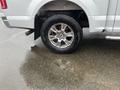 A 2016 Ford F-150 with a chrome wheel and a newly installed tire standing on wet pavement