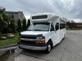 A white 2017 Chevrolet Express shuttle bus with a large windshield and side windows parked at an angle