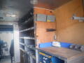 Interior of a 2008 Freightliner MT45 Chassis featuring metal shelving along the walls and a workbench with storage bins and tools