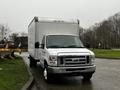 A 2017 Ford Econoline with a white cargo box and front grille featuring the Ford logo parked on a gray surface