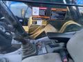 Interior view of a 2014 John Deere 350G with controls and safety warning labels visible on the dashboard and joystick