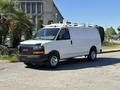 A white 2019 GMC Savana van with a roof rack parked on a street