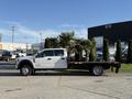 A 2020 Ford F-550 flatbed truck in white with a black flatbed and a crew cab parked on a paved surface