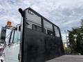 A 1998 Freightliner FL80 truck with a black mesh back and an orange flashing light on top