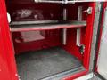 An empty compartment inside a red 1991 Sutphen Deluge fire truck featuring metal shelving and a textured rubber floor