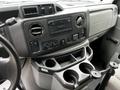 Interior of a 2013 Ford Econoline featuring dashboard controls a radio panel climate controls and cup holders