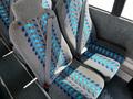 Two rows of bus seats with blue and teal striped patterns and seatbelts installed
