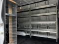 Interior of a 2020 Mercedes-Benz Sprinter van featuring metal shelving and storage compartments without cargo