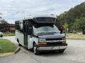 A 2019 Chevrolet Express shuttle bus with a black front and silver body parked at an angle facing the viewer