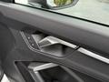 Close-up of the interior door panel of a 2024 Audi Q3 featuring a sleek handle and control buttons for locking and unlocking the doors