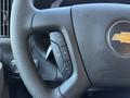 Close-up of the steering wheel of a 2024 Chevrolet Express featuring control buttons for cruise and audio settings with a silver Chevrolet logo in the center